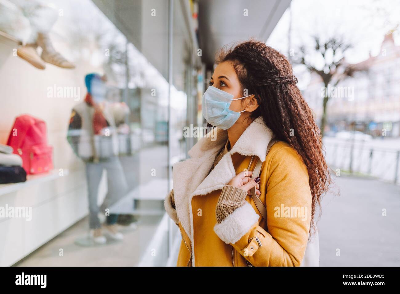 Belle femme aux cheveux afro portant un support de masque médical de  protection sur la rue de la ville et regarder la fenêtre de magasin Photo  Stock - Alamy