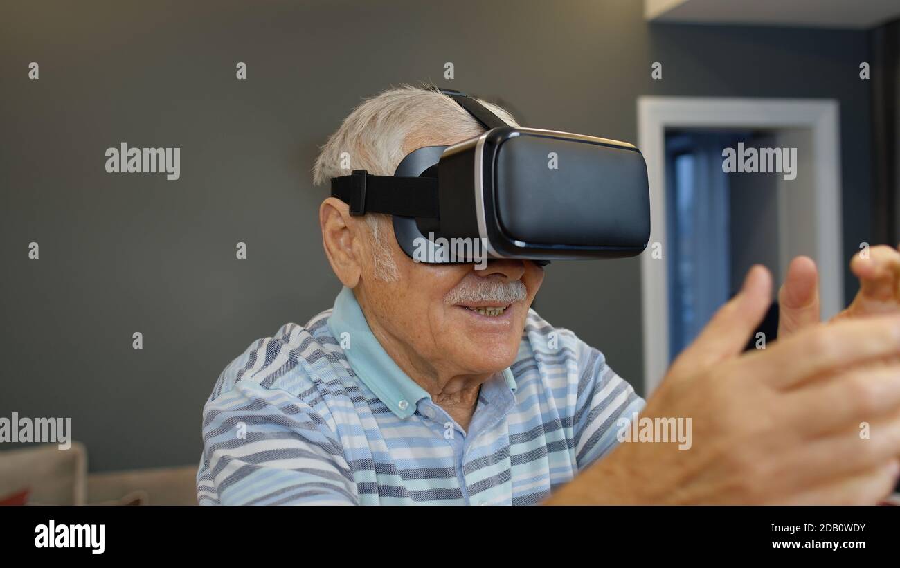 Grand-père émerveillé dans des lunettes de casque virtuel en regardant une  vidéo 3D incroyable dans un casque VR 360 à la maison. Technologie future.  L'homme dans des lunettes VR jouant à des