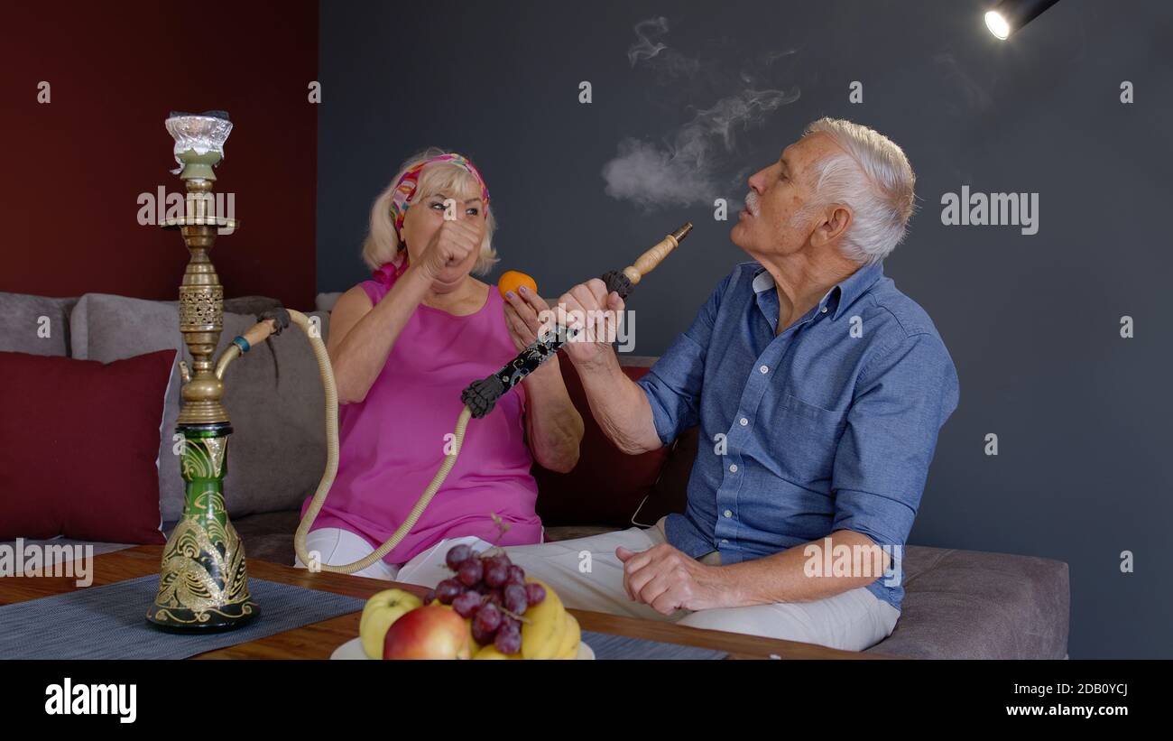 Un Vieux Couple Joyeux Qui Fume Du Narguile Mangeant Des Fruits Celebrant L Anniversaire De Sa Retraite Dans Le Salon A La Maison Grand Mere Et Grand Pere Ages Ayant Du Plaisir Appreciant La Relation