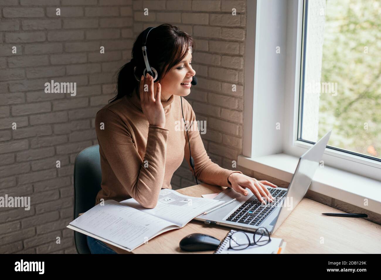 Jeunes femmes focalisées portant des écouteurs étudier en ligne à la maison Banque D'Images