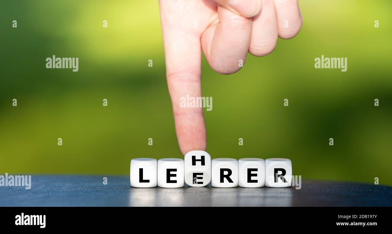 La main tourne les dés et change le mot allemand 'Leerer' (vide) en 'Lehrer' (enseignant). Banque D'Images