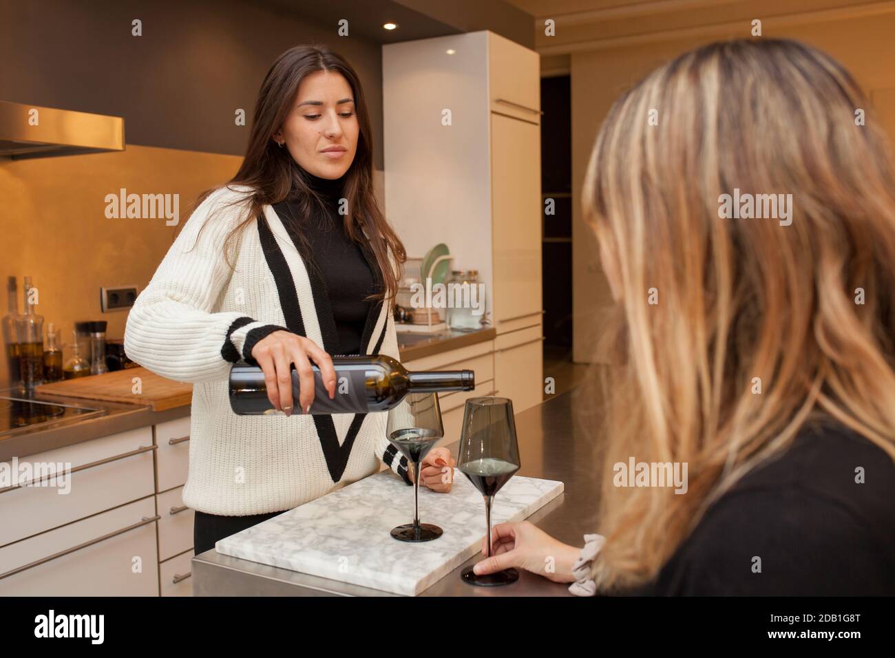 Deux belles femmes préparant une tasse de vin rouge la cuisine Banque D'Images