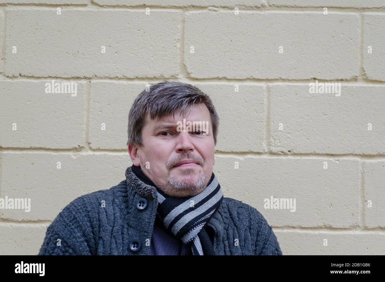 Portrait de l'homme avec l'expression d'une légère perplexité sur son visage. Homme grisâtre d'âge moyen se dresse dans une posture étonnamment sombre avec un sourire léger sur son f Banque D'Images