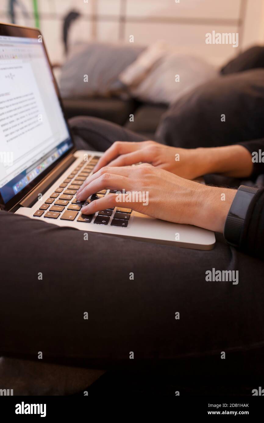 Femme travaillant les mains avec un ordinateur portable assis sur le canapé Banque D'Images