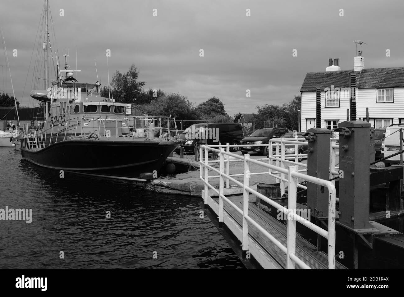 Un canot de sauvetage à la retraite amarré à Heybridge Essex UK avec des bâtiments d'époque en arrière-plan en noir et blanc Banque D'Images
