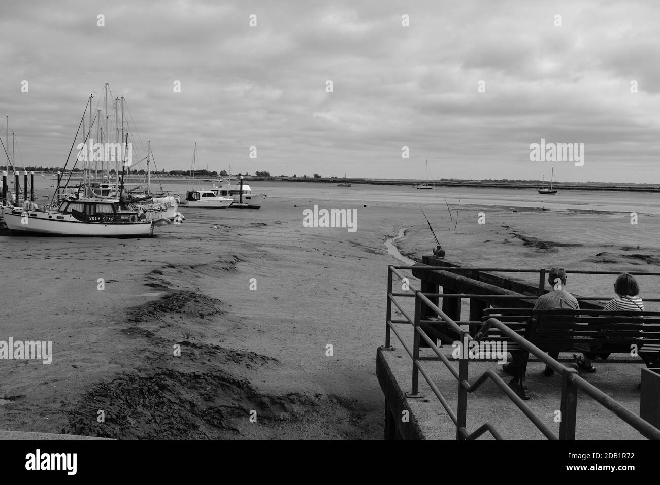 bateaux à l'ancre et assis couple regardant la vue avec Tide Out à Heybridge Essex, Royaume-Uni Banque D'Images