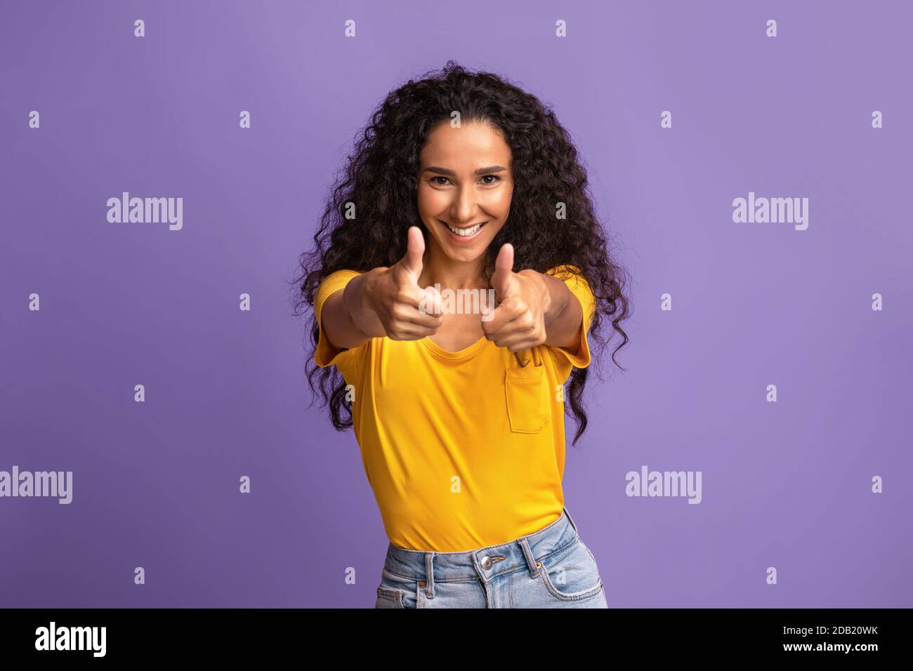 Joyeuse brune femme gestante pouce vers le haut à l'appareil photo, debout fond violet Banque D'Images