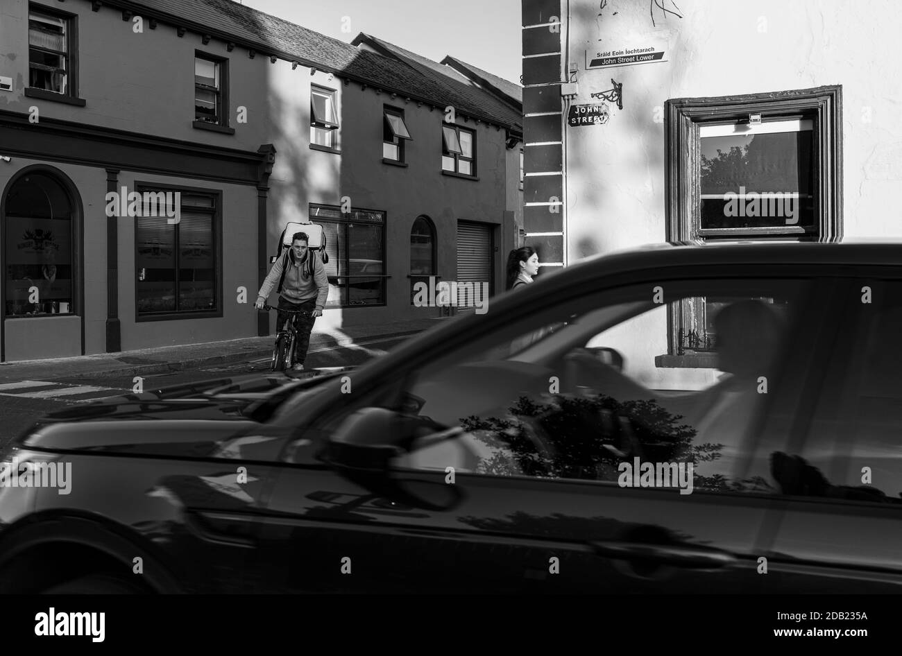 Livraison de nourriture cycliste et passersby sur la rue John à l'extérieur de la maison publique Brogans à Kilkenny, comté de Kilkenny, Irlande Banque D'Images