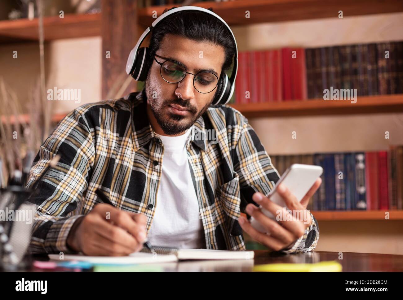 Étudiant indien Guy utilisant l'apprentissage de smartphone dans la bibliothèque de l'université Banque D'Images