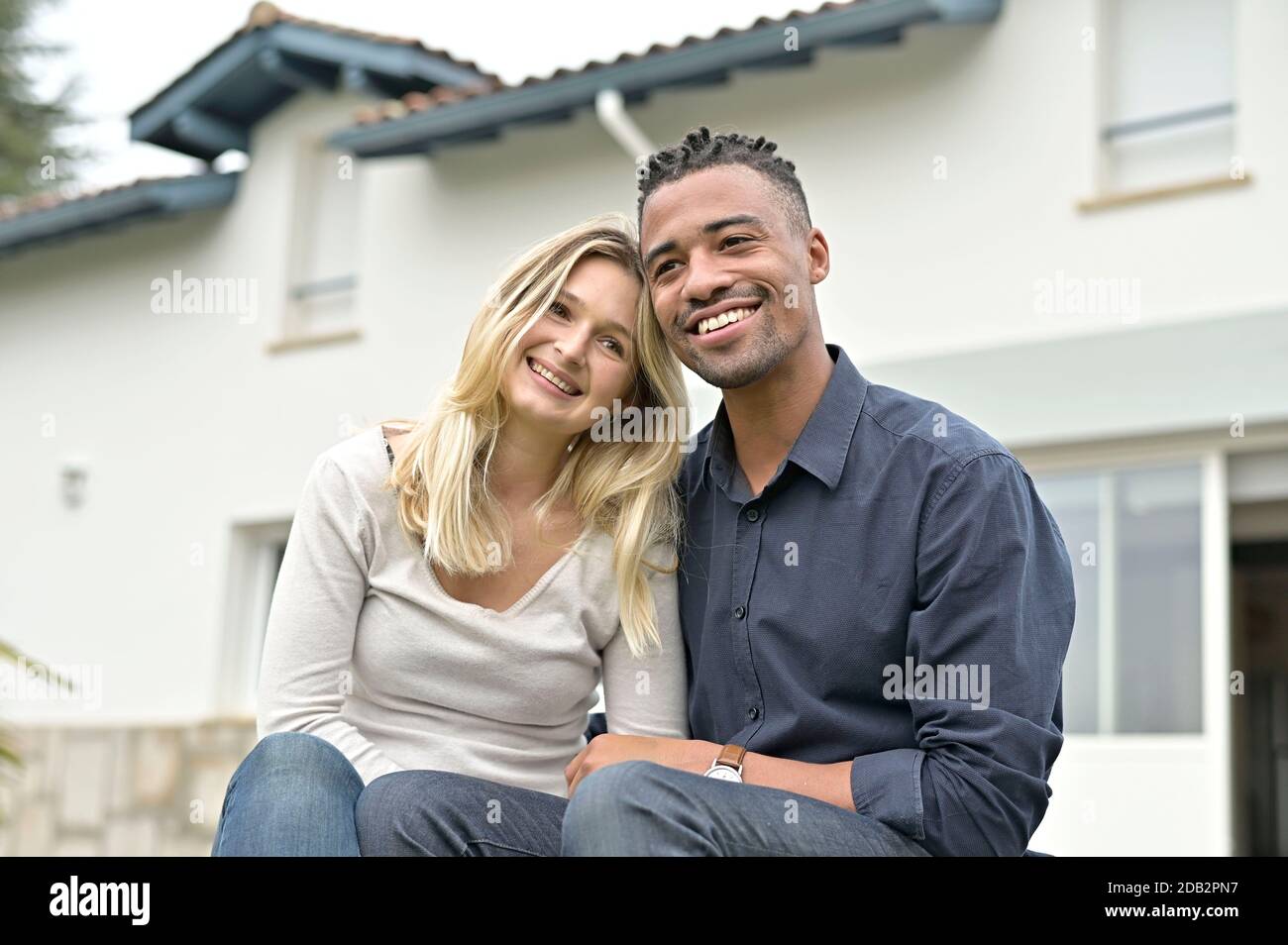 Heureux couple de course mixte assis devant leur nouveau accueil Banque D'Images
