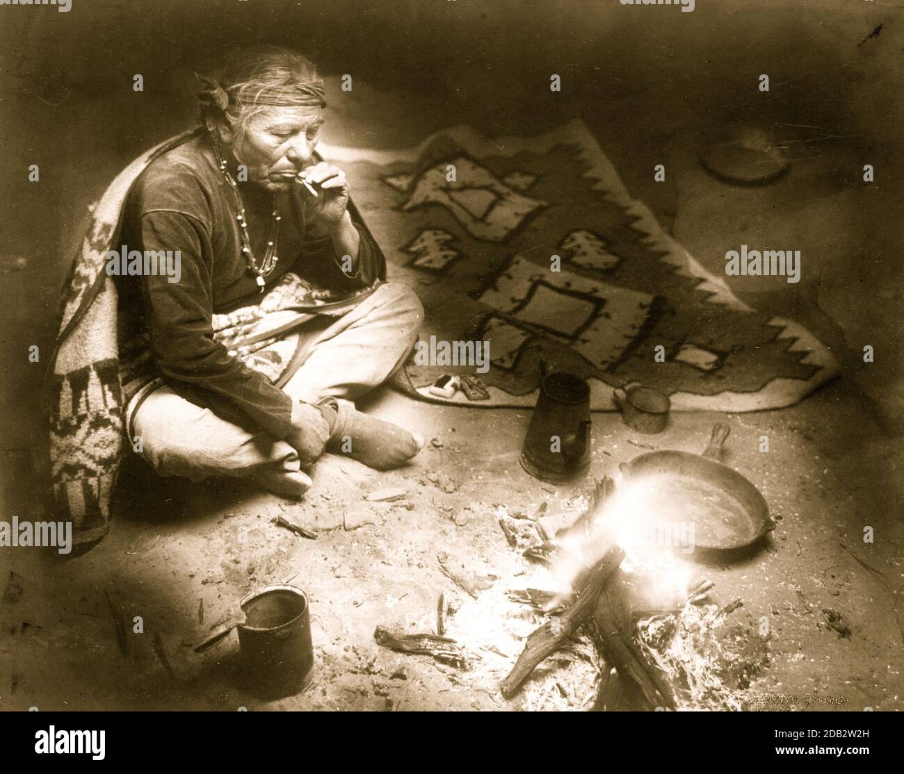 Navajo Indien, assis près d'un feu de camp, fumer la cigarette. Banque D'Images