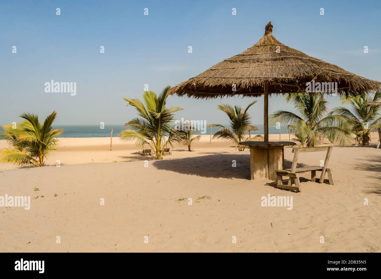 Parasol en paille avec un petit banc en bois et une table sur la plage de  Bijilo en Gambie Photo Stock - Alamy