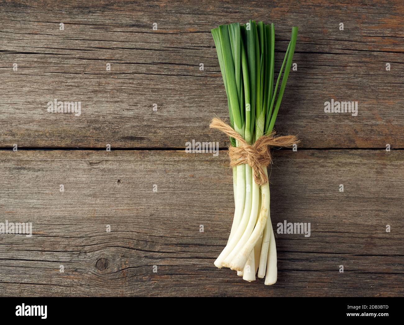 feuilles d'oignon vert frais attachées avec une corde dans un bouquet sur un fond gris en bois, vue de dessus Banque D'Images