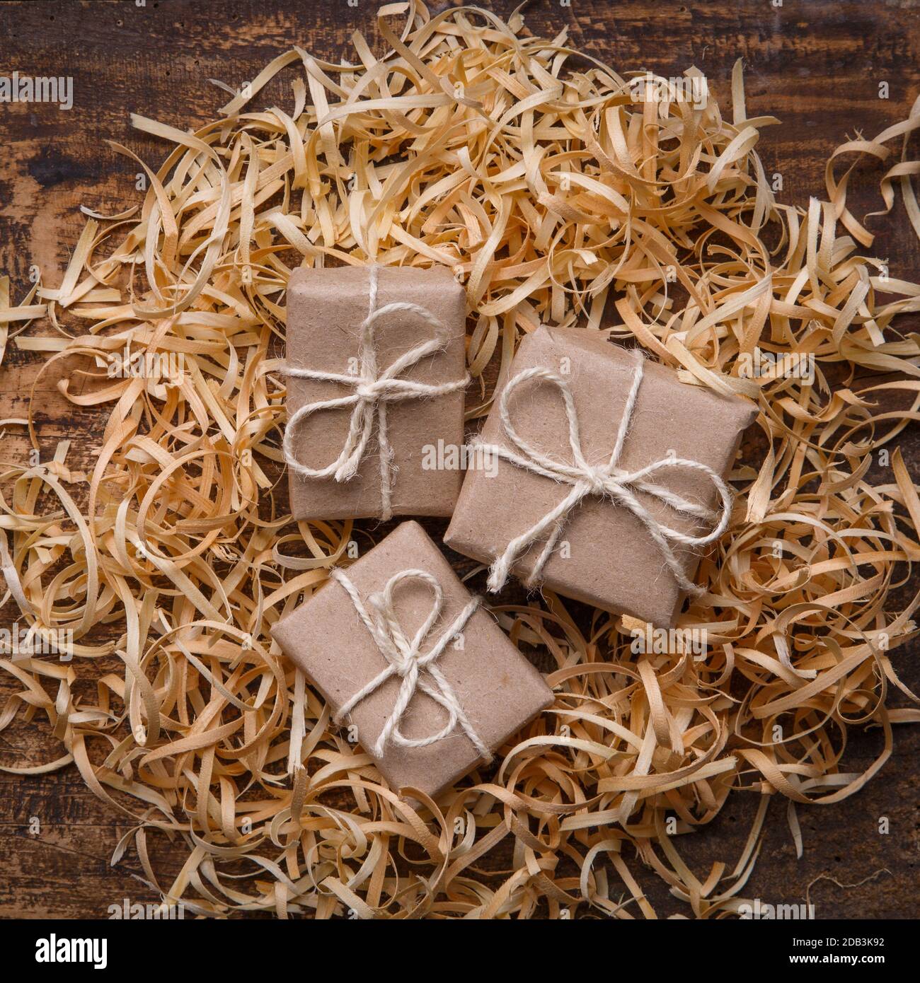 Trois petits cadeaux sont enveloppés dans du papier kraft et coulés dans des copeaux de bois. Concept de cadeau fait main, emballage écologique. Style rustique. Vue de dessus Banque D'Images