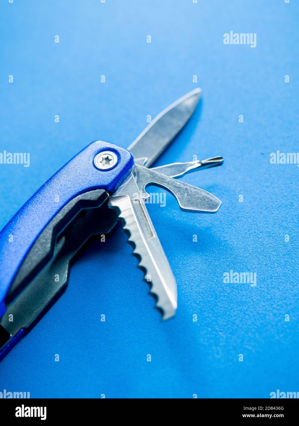 Un gros plan vertical des lames sur un utilitaire de poche outil sur une surface bleue Banque D'Images