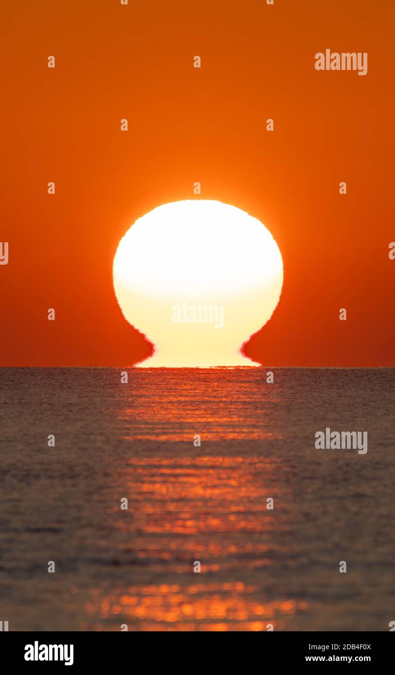 Portrait d'un coucher de soleil sur la mer. Verticale du coucher de soleil sur l'océan avec le soleil touchant l'eau. Banque D'Images