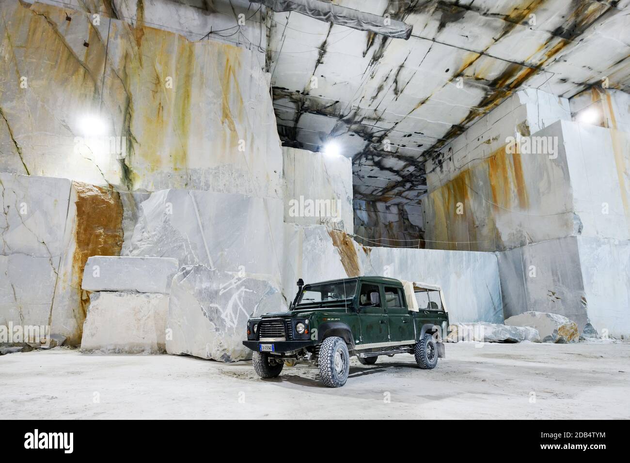Land Rover Defender stationné dans une carrière de marbre de Carrare Toscane Italie à côté de la face de roche coupée pendant les opérations minières Banque D'Images