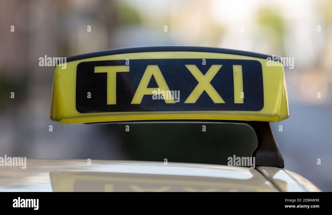 Panneau de taxi sur un toit de voiture, texte jaune et noir, vue rapprochée, taxi sur la rue de la ville à l'heure de la journée attendant le passager, flou paysage urbain arrière Banque D'Images