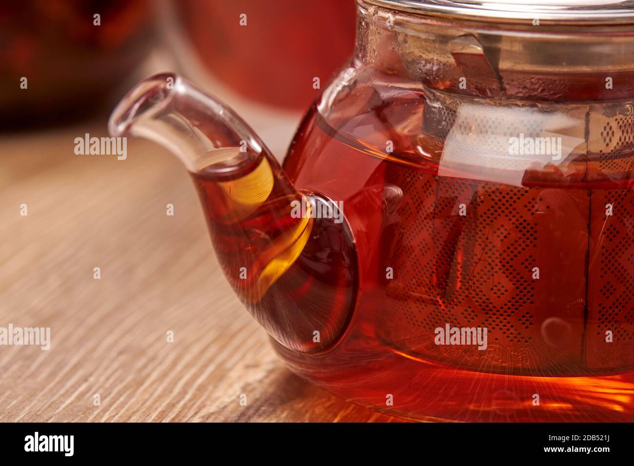 Gros plan d'un thé chaud dans une théière en verre transparent sur la table avec réflexion. Banque D'Images