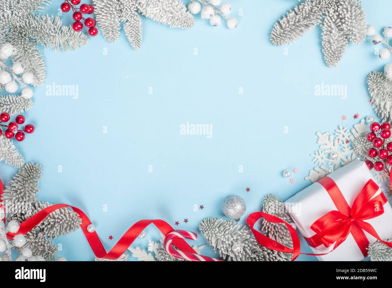 Brindilles de sapin dépoli et boules décoratives de Noël et cadeau avec ruban rouge sur fond bleu avec espace de copie pour le modèle de texte, posez-le à plat sur Banque D'Images