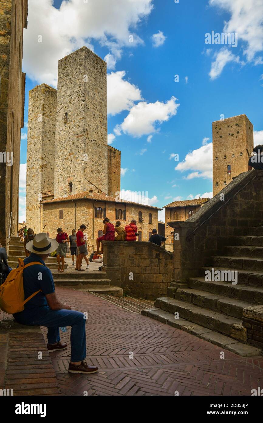 Touristes sur la Piazza Duomo avec les tours jumelles Torri dei Savucci, Torre Pettini et Torre Chigi dans la ville médiévale de San Gimignano, Toscane, Italie Banque D'Images