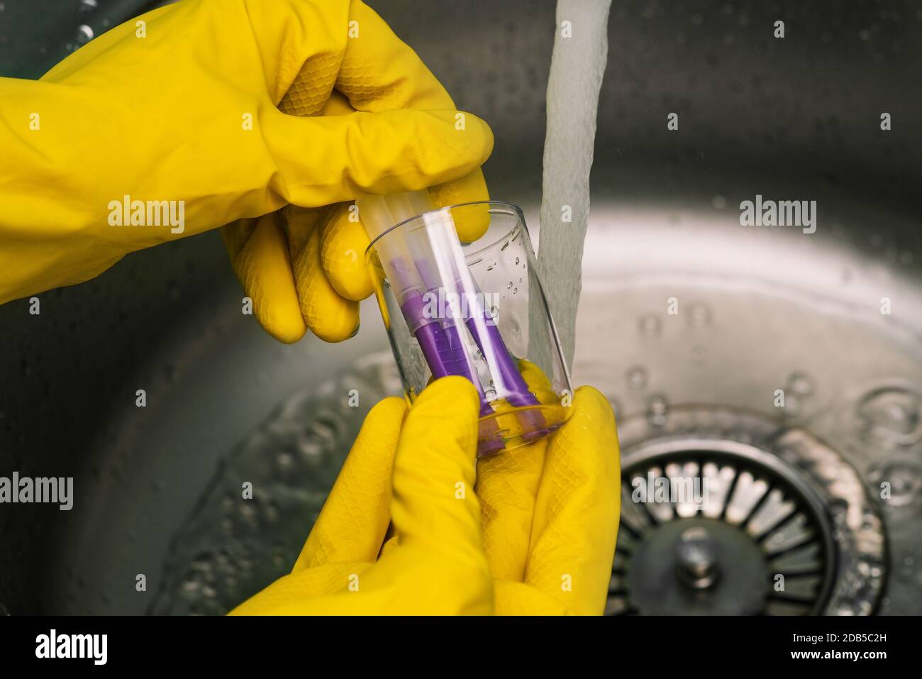 Un scientifique rinçant des tubes Covid-19 dans le laboratoire. Gants de protection jaunes. Bactériologie du coronavirus, virologie, ADN et soins de santé Banque D'Images