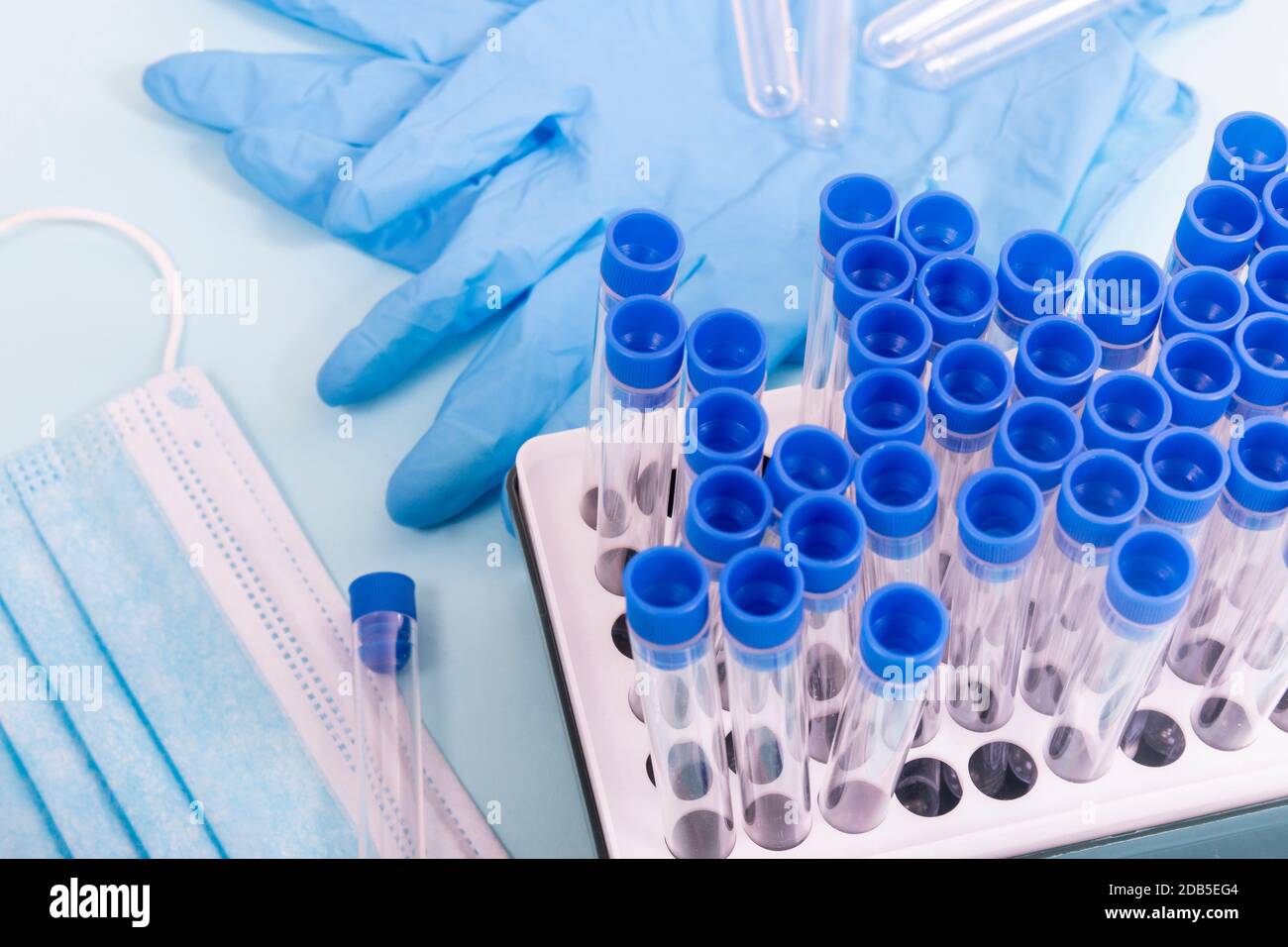 Plusieurs objets de laboratoire, dont un masque de protection, un portoir pour flacons, des tubes de test et d'autres produits. Banque D'Images