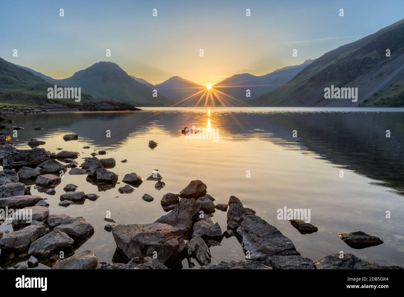 Vue paisible sur Wastwater dans le Lake District quand le soleil se lève à travers les montagnes. Banque D'Images