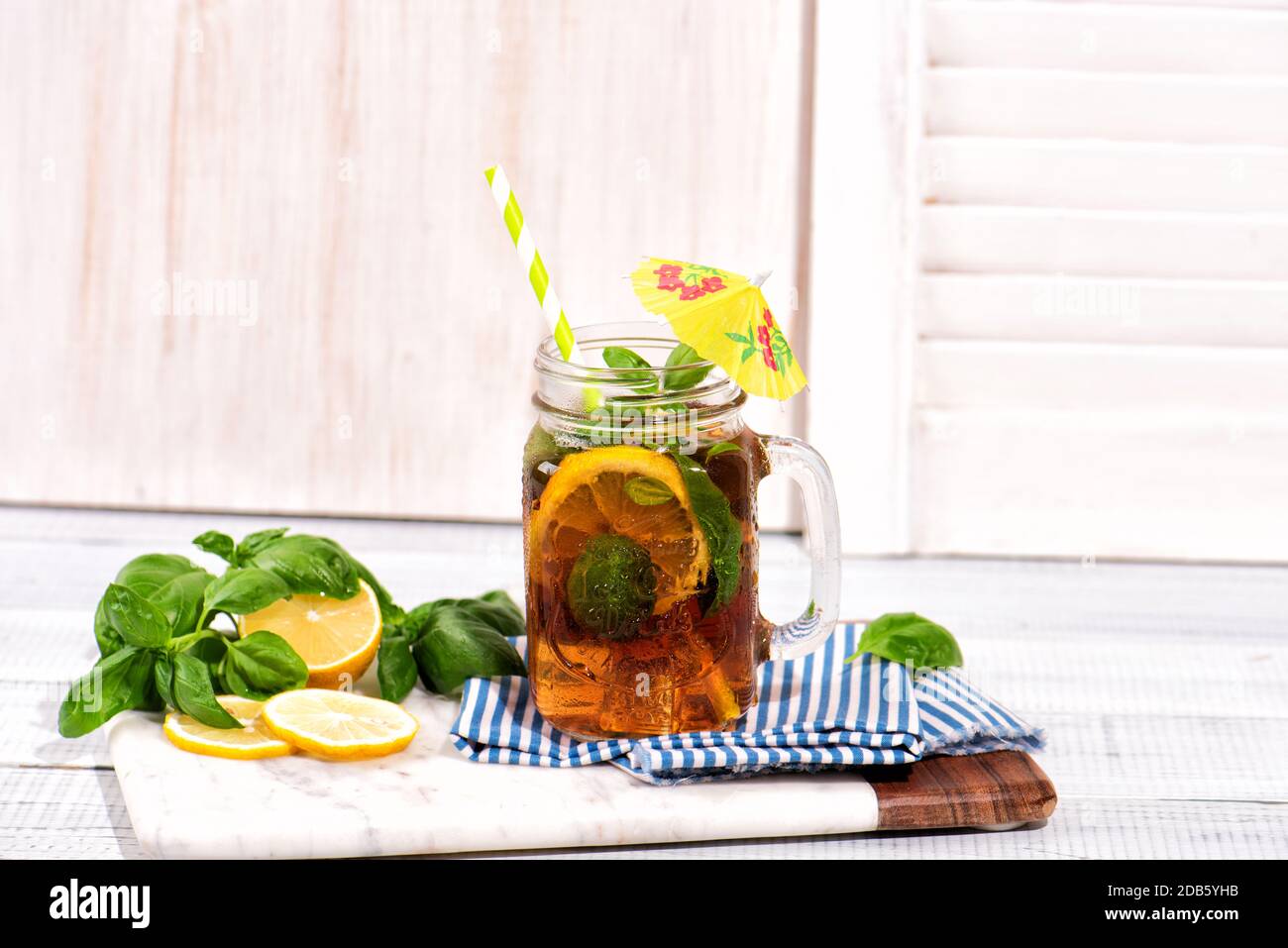 Le verre de thé glacé sur une table en bois. Cuba libre ou long Island cocktail, boisson froide ou limonade avec citron et basilic. Banque D'Images