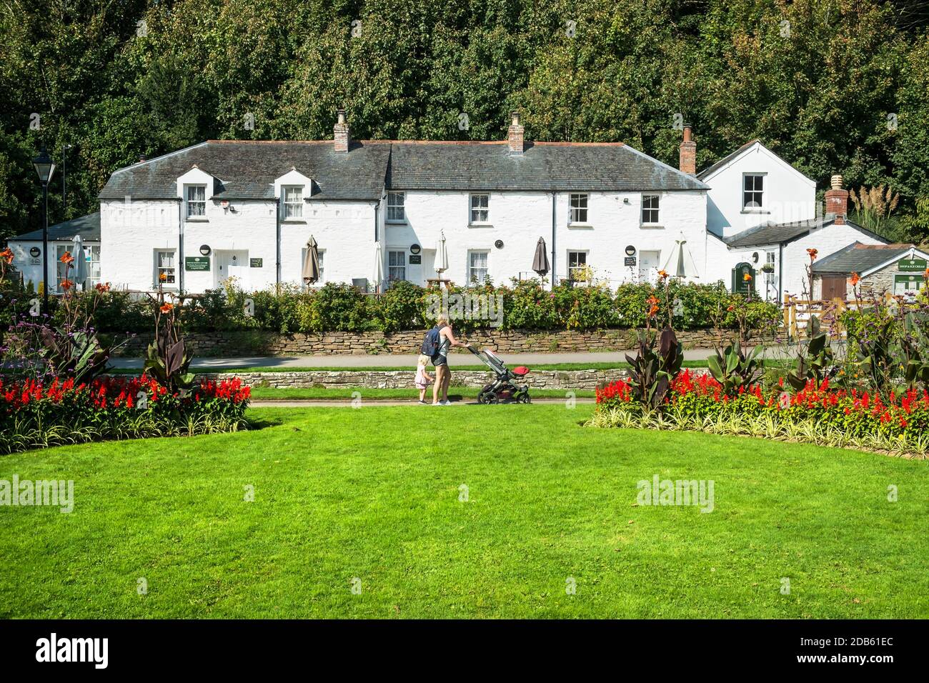 Une mère et sa petite fille marchant devant les cottages du patrimoine dans les jardins subtropicaux de Trenance à Newquay, dans les Cornouailles. Banque D'Images