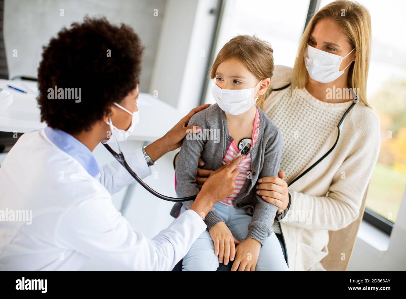 Mère avec sa petite fille à l'examen pédiatre par Femme afro-américaine médecin Banque D'Images