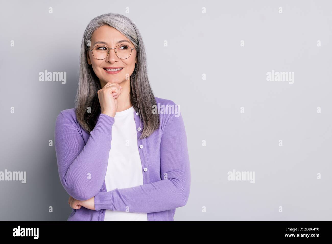 Photo portrait d'une femme d'affaires intelligente et aînée qui porte des lunettes regarder côté penser à l'idée touchant visage souriant isolé en gris Banque D'Images