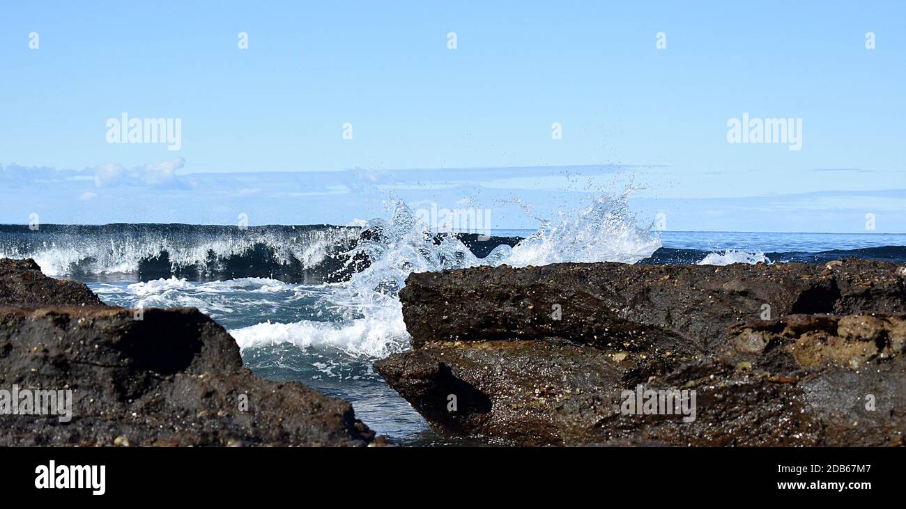 Plage avec une vague de crashing et des rochers Banque D'Images