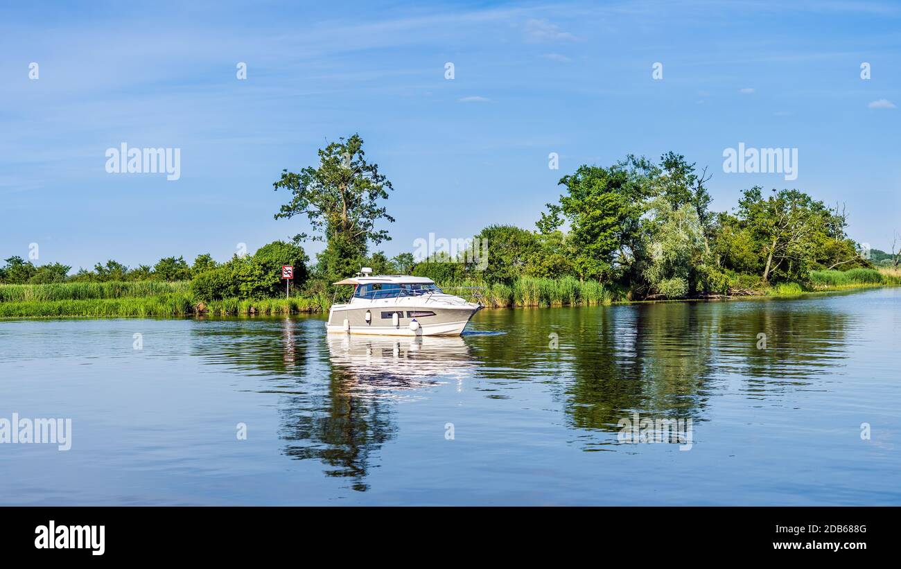 Bateau à moteur flottant sur la rivière ou le lac avec des roseaux et des tentatives de rivière verte, belle journée d'été sur la marina de bateaux Szczecin, Pologne Banque D'Images