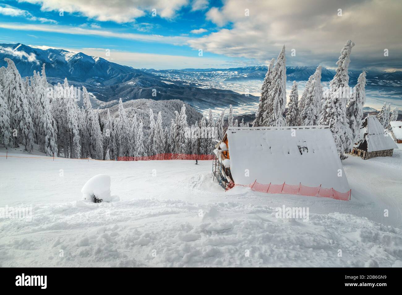 Paysage hivernal enneigé et pistes de ski dans la forêt de pins. Chalets alpins confortables et enneigés à proximité de fantastiques pistes de ski, Poiana Brasov, Carpates, Transy Banque D'Images