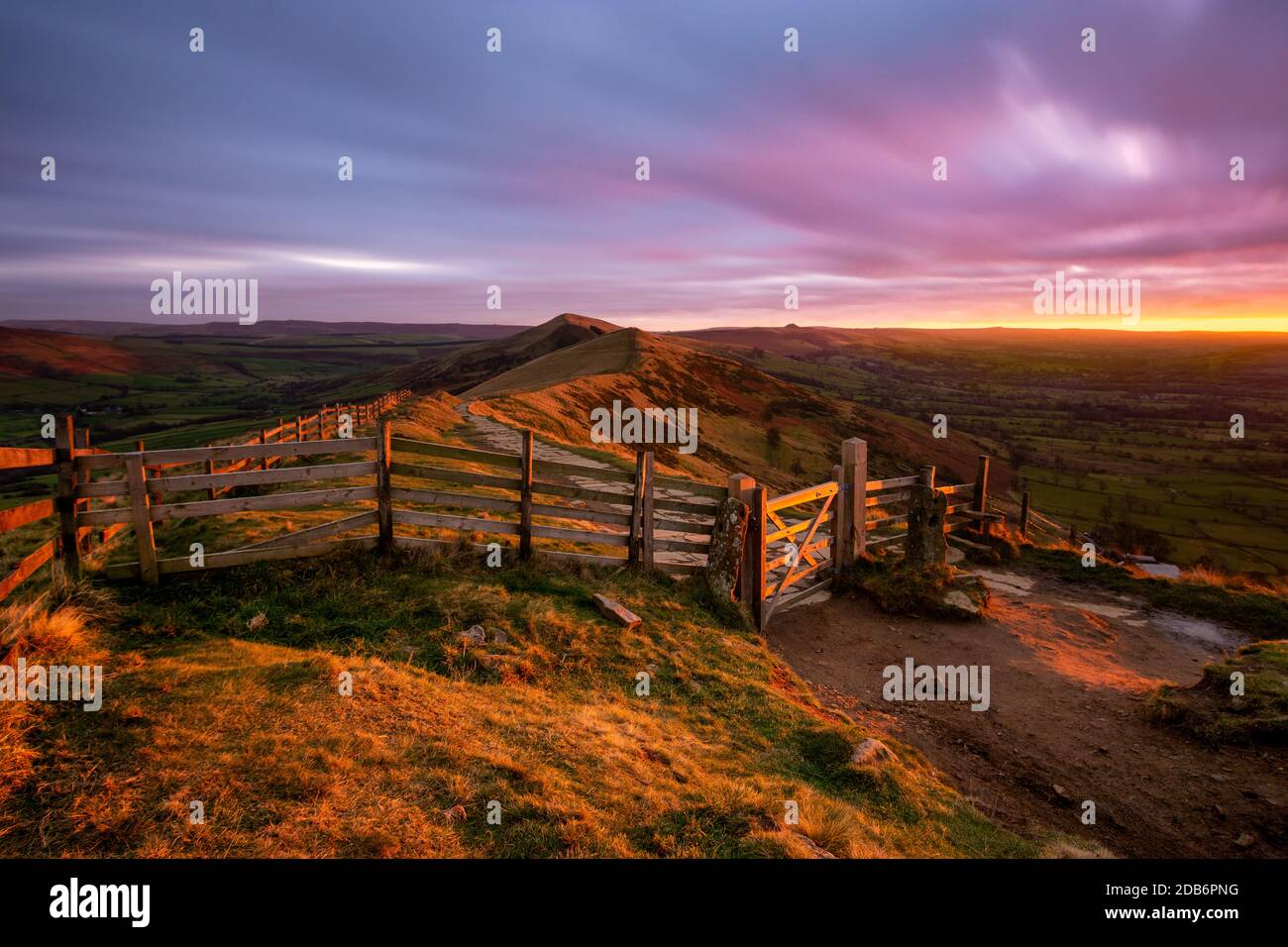 Lumière rouge éclatante du soleil levant qui brille sur la porte de campagne de MAM Tor dans le Peak District avec des nuages moody. Banque D'Images