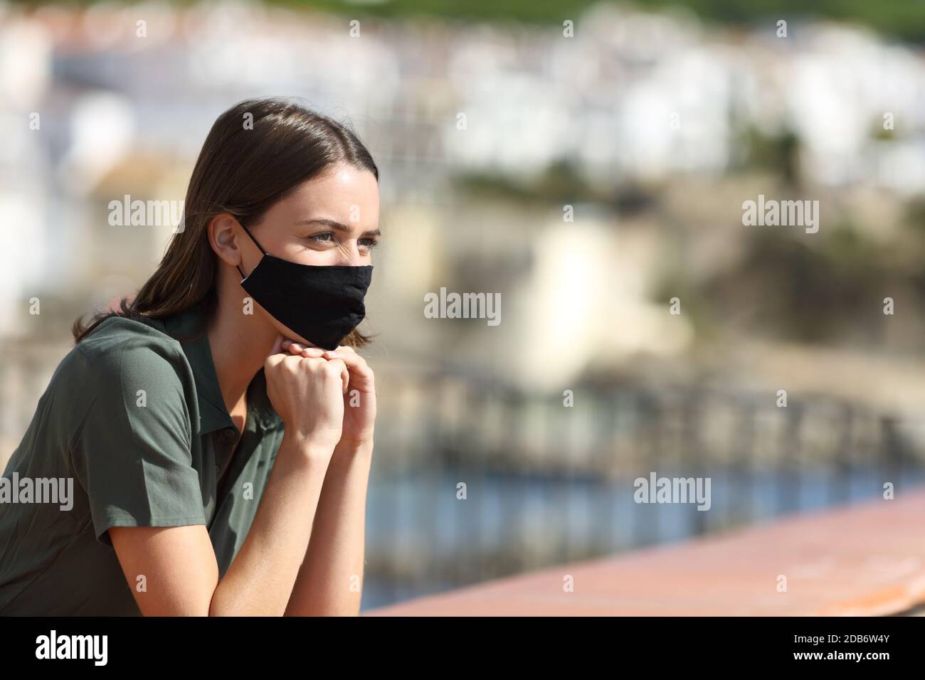 Femme heureuse portant un masque évitant la contagion du coronavirus en contemplant des vues vacances depuis un balcon Banque D'Images