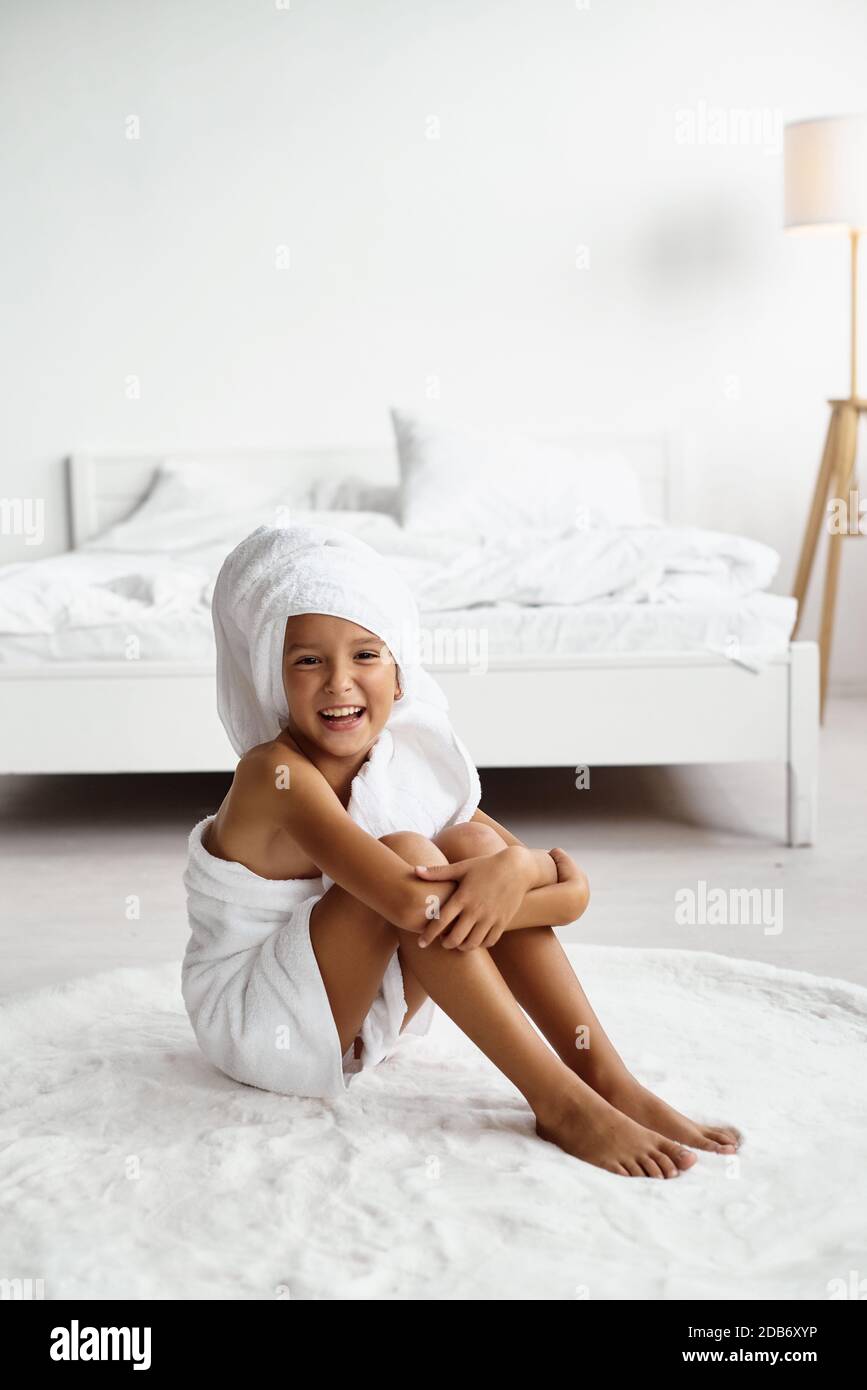 Portrait d'une petite fille mignonne avec des cheveux enveloppés dans une  serviette de bain après un bain ou une douche. Les enfants s'amusent dans  une chambre d'hôtel lumineuse. Procédure spa, bain tex
