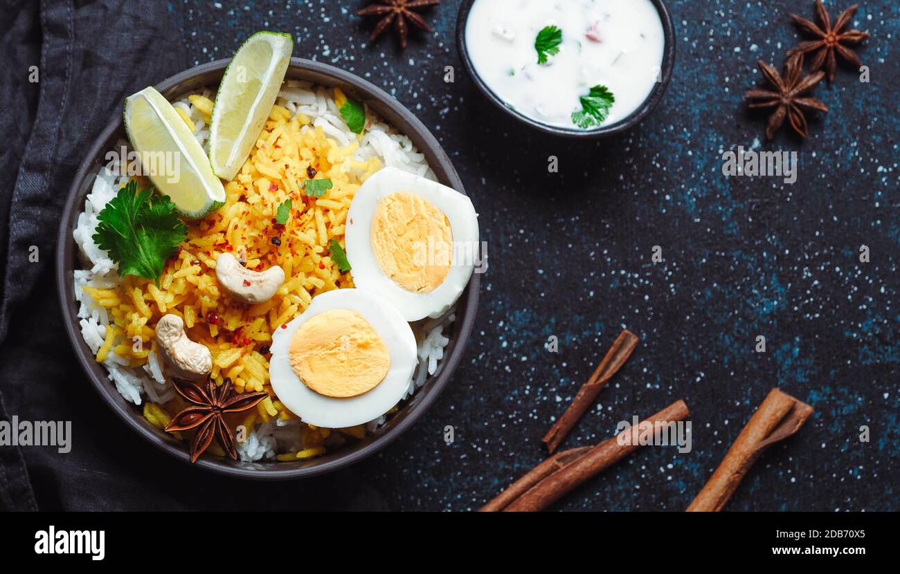 Vue sur le plateau de riz de l'Indian Egg Biryani ou de l'anda sur fond sombre. Egg Biryani - riz basmati cuit avec des œufs et des épices rôtis au masala, servi avec du yaourt Banque D'Images