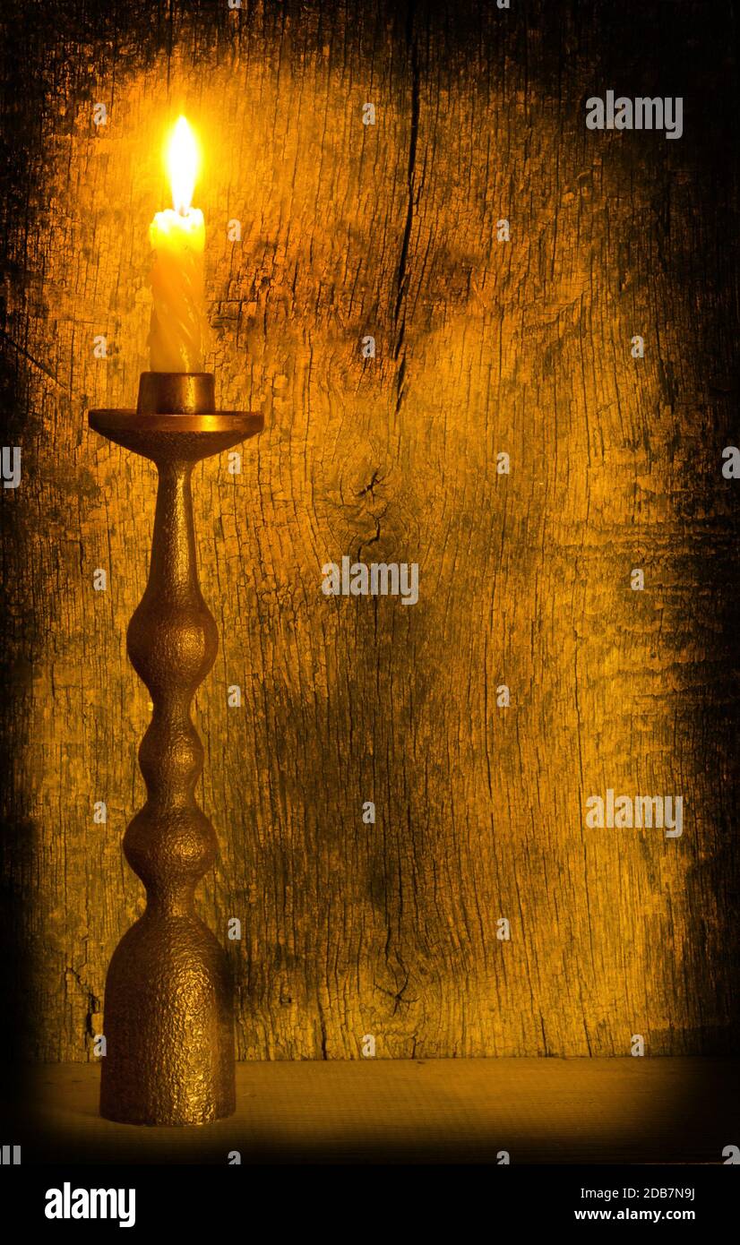 Une bougie allumée dans un chandelier sur un fond en bois Banque D'Images