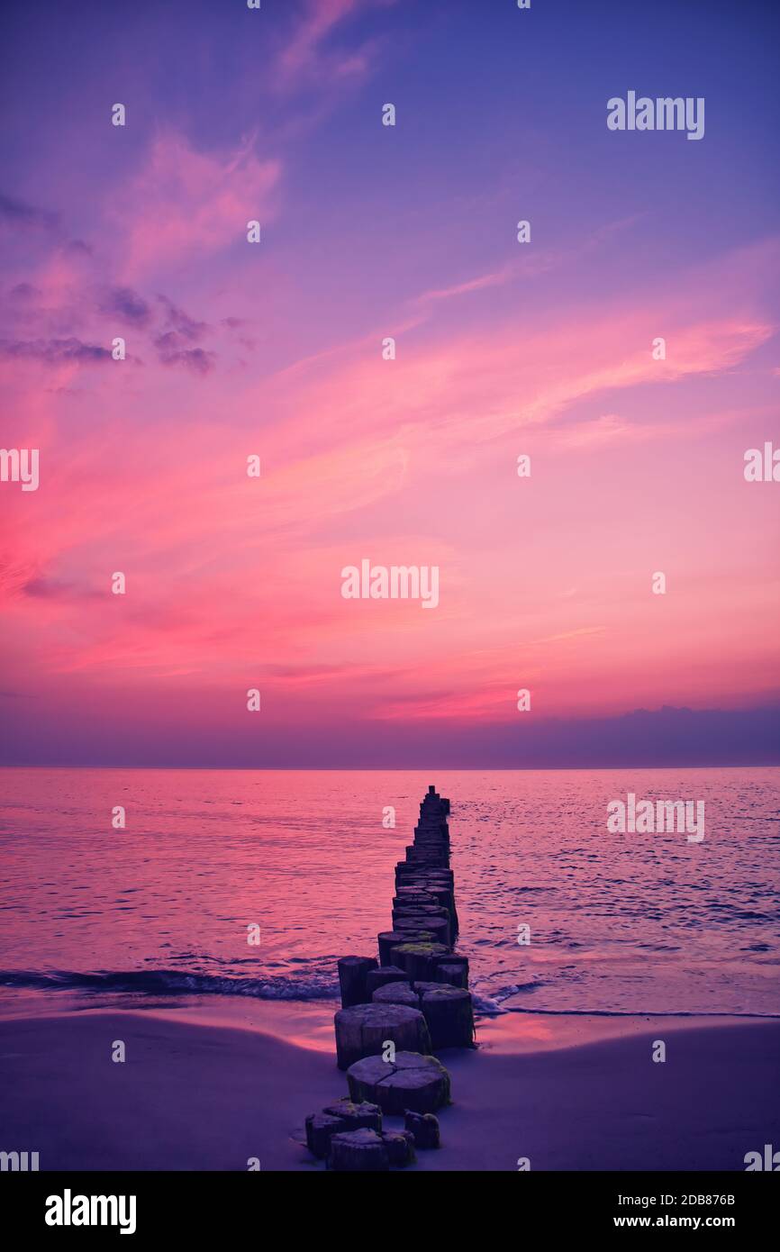 une groyne en bois dépasse dans la mer baltique au coucher du soleil Banque D'Images