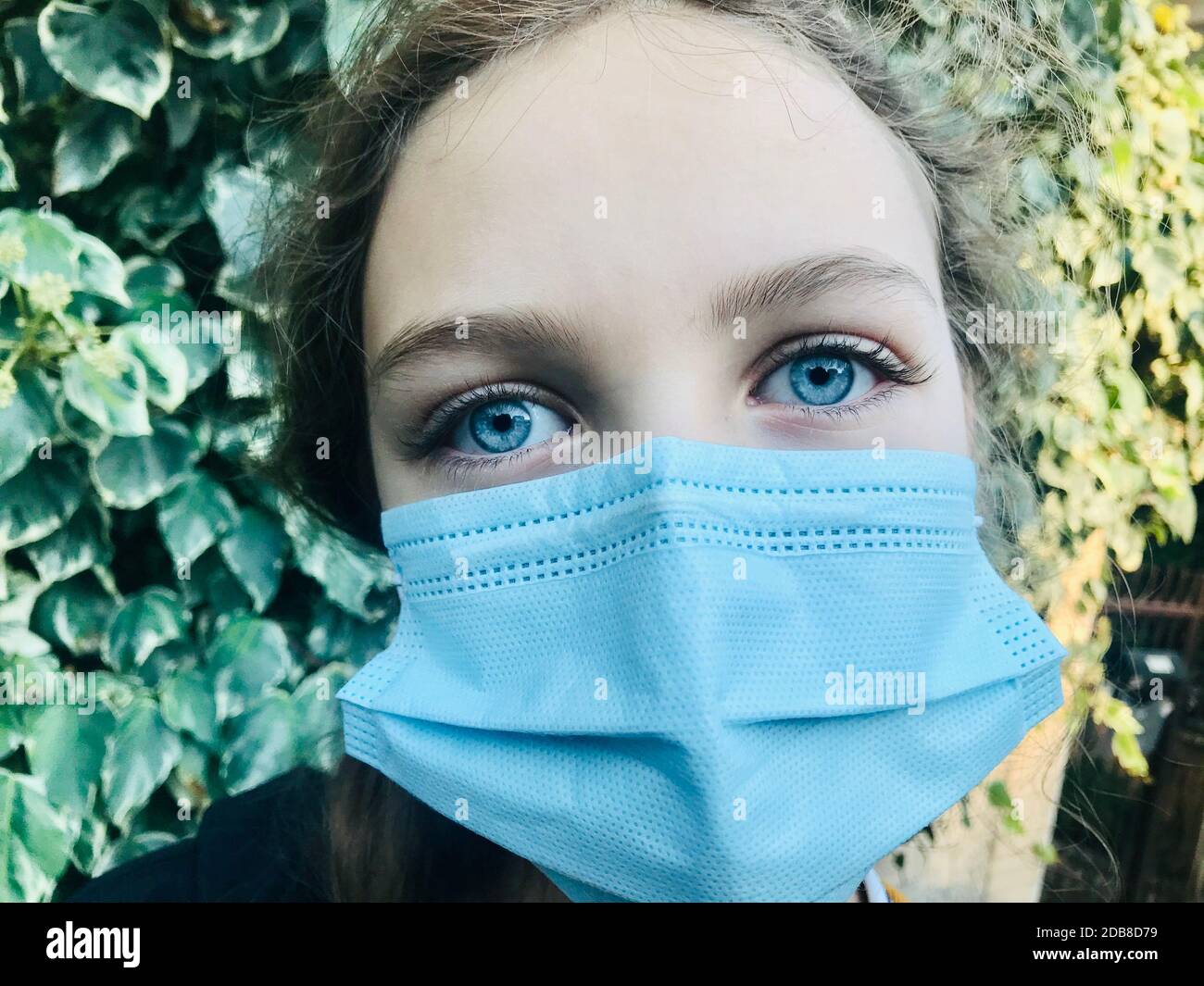 Portrait d'une fille avec yeux bleus perçant portant un masque facial Banque D'Images