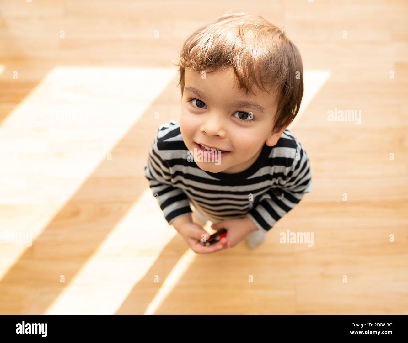 Tout-petit regardant et souriant à l'appareil photo dans des couleurs vives chambre ensoleillée Banque D'Images