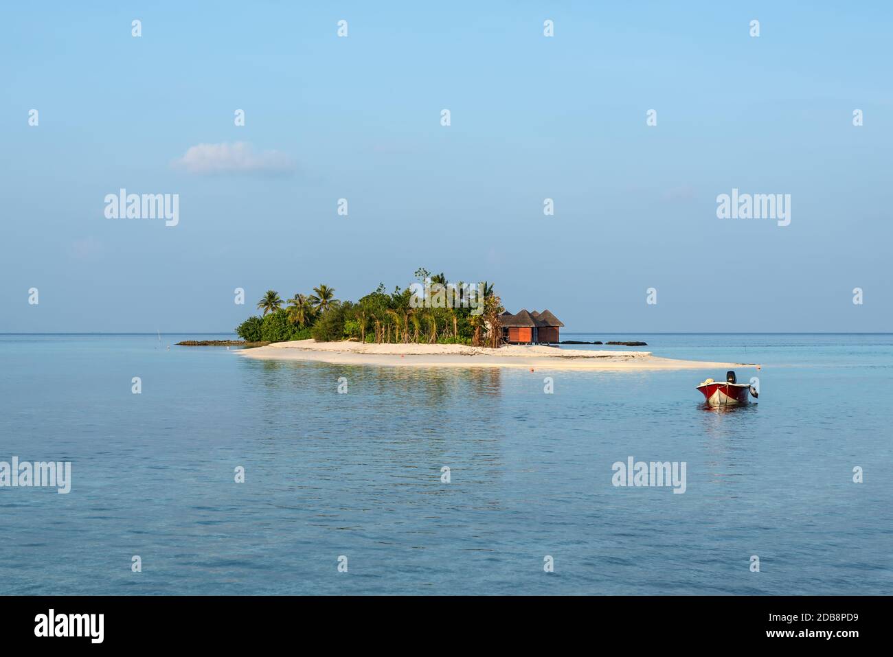 Paysage avec une petite île dans les Maldives, l'Océan Indien, l'Atoll de Kaafu, Kuda Huraa Island. Un bateau à moteur est ancrée dans l'avant-plan. Banque D'Images