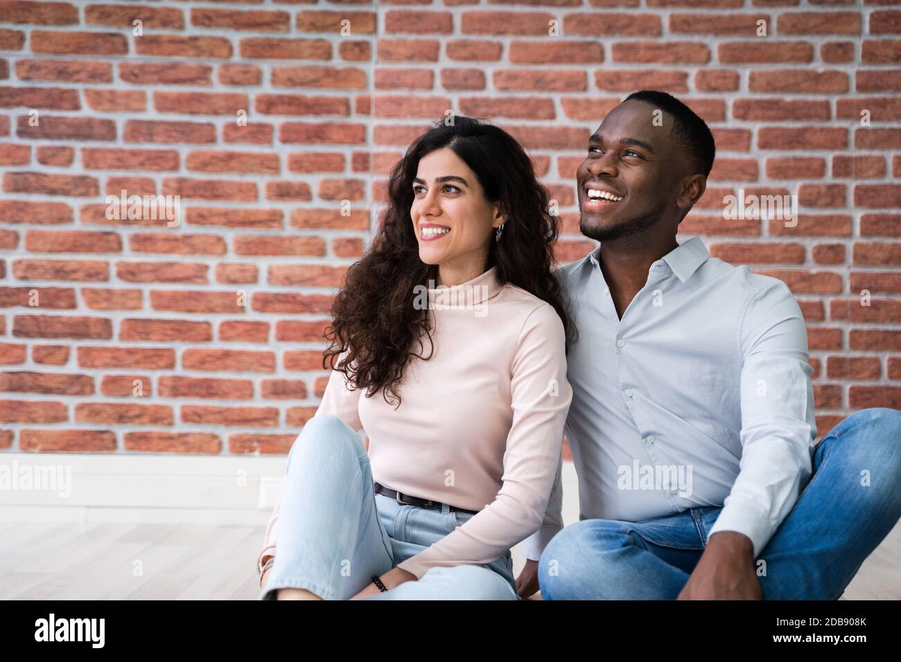 Portrait de jeunes couples multiethniques assis sur le sol dans leur nouvelle maison Banque D'Images