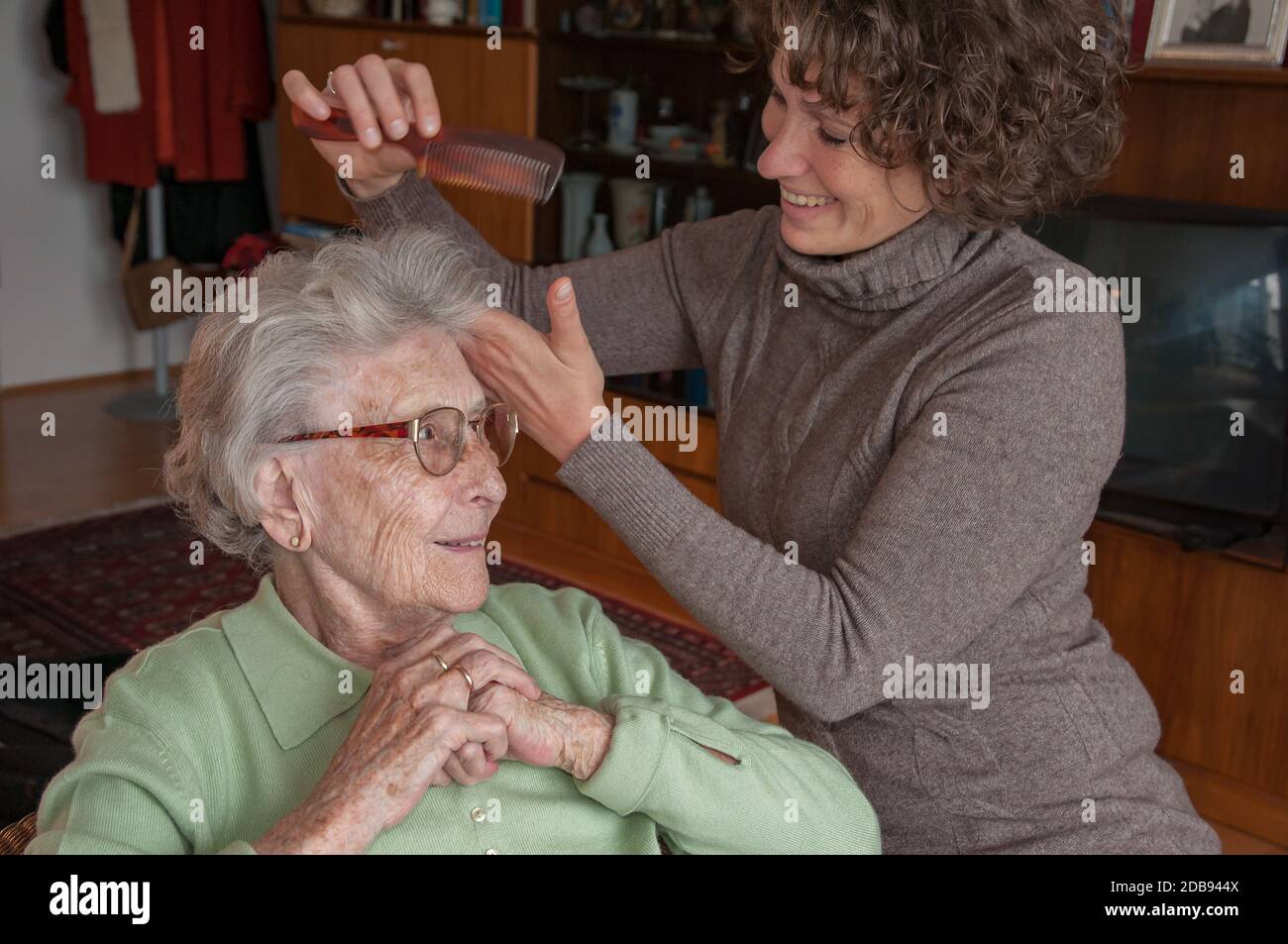 La femme âgée obtient son style de cheveux par le soignant Banque D'Images