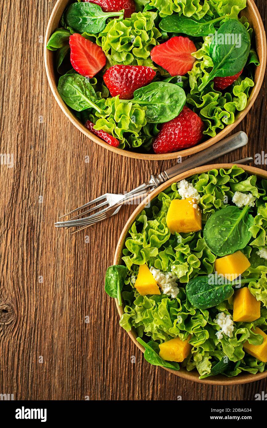 Salade verte saine avec fruits à la mangue et aux fraises et fromage frais sur fond de table en bois. Repas de salade sain. Banque D'Images