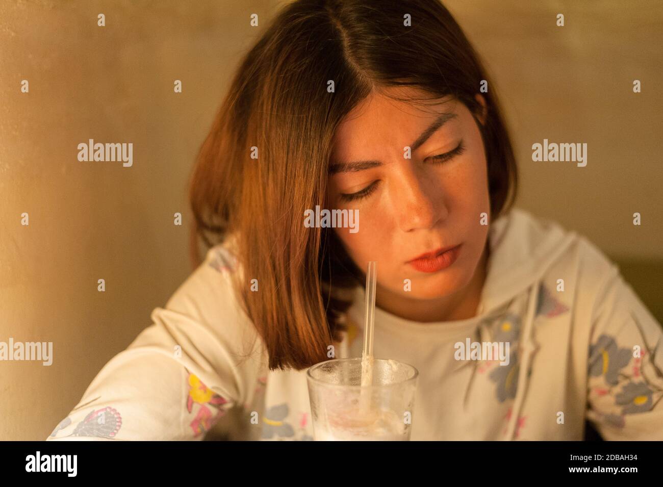 belle jeune femme brunette se trouve bien près d'un verre avec du café latte Banque D'Images