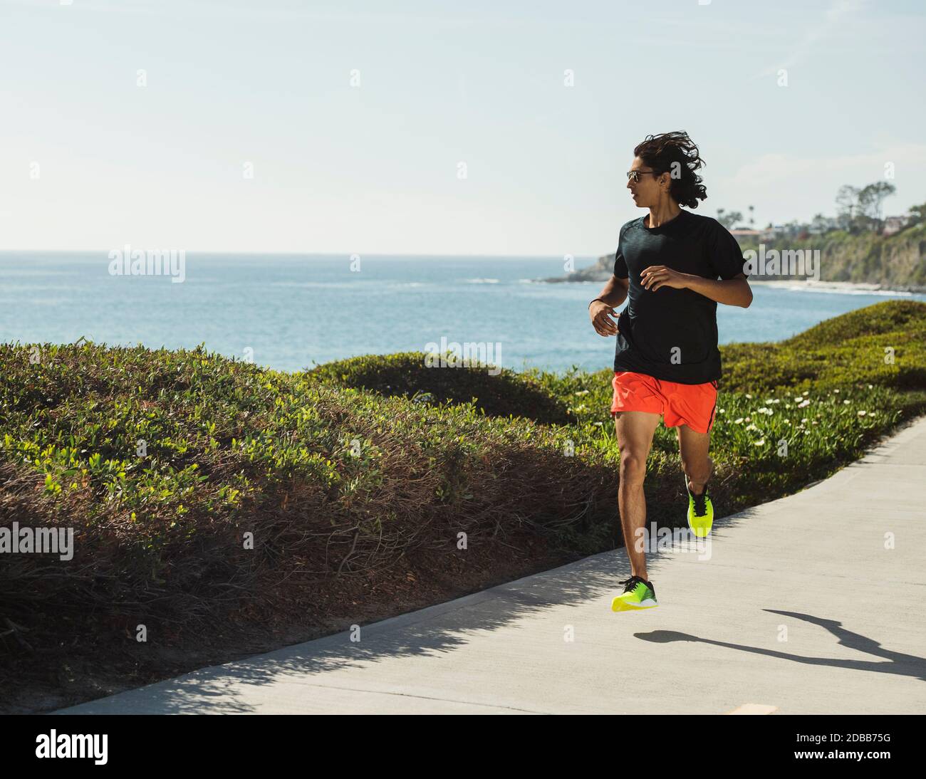 États-Unis, Californie, Dana point, homme en train de courir sur la route par la côte Banque D'Images
