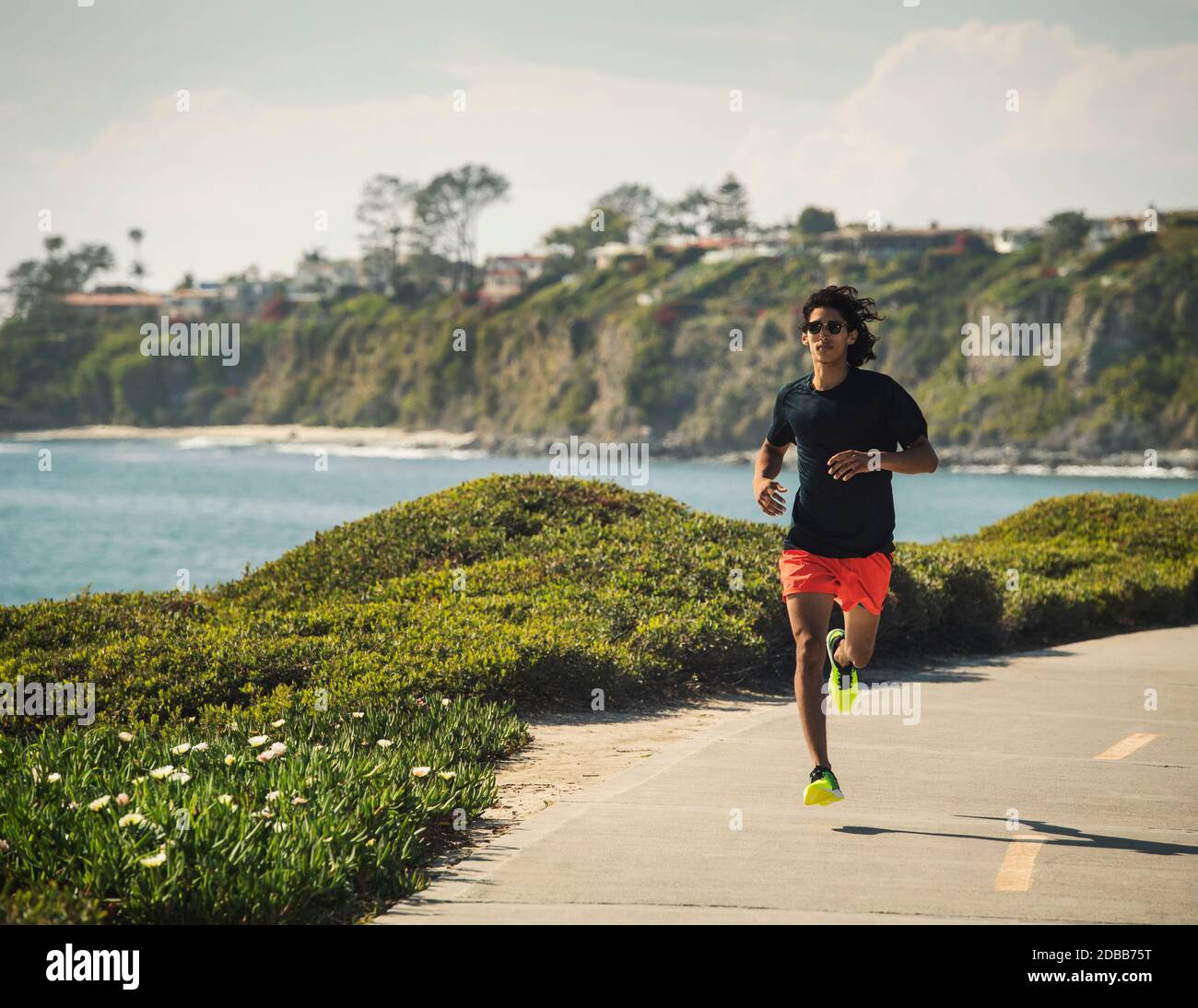 États-Unis, Californie, Dana point, homme en train de courir sur la route par la côte Banque D'Images